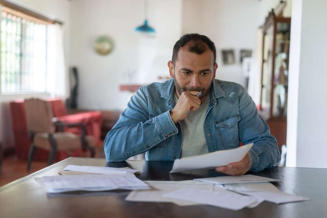 Latin American low income man checking his home finances and looking worried while looking at the utility bills - lifestyle concepts