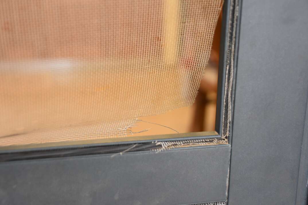 A residential screen door with a tear due to a dog 