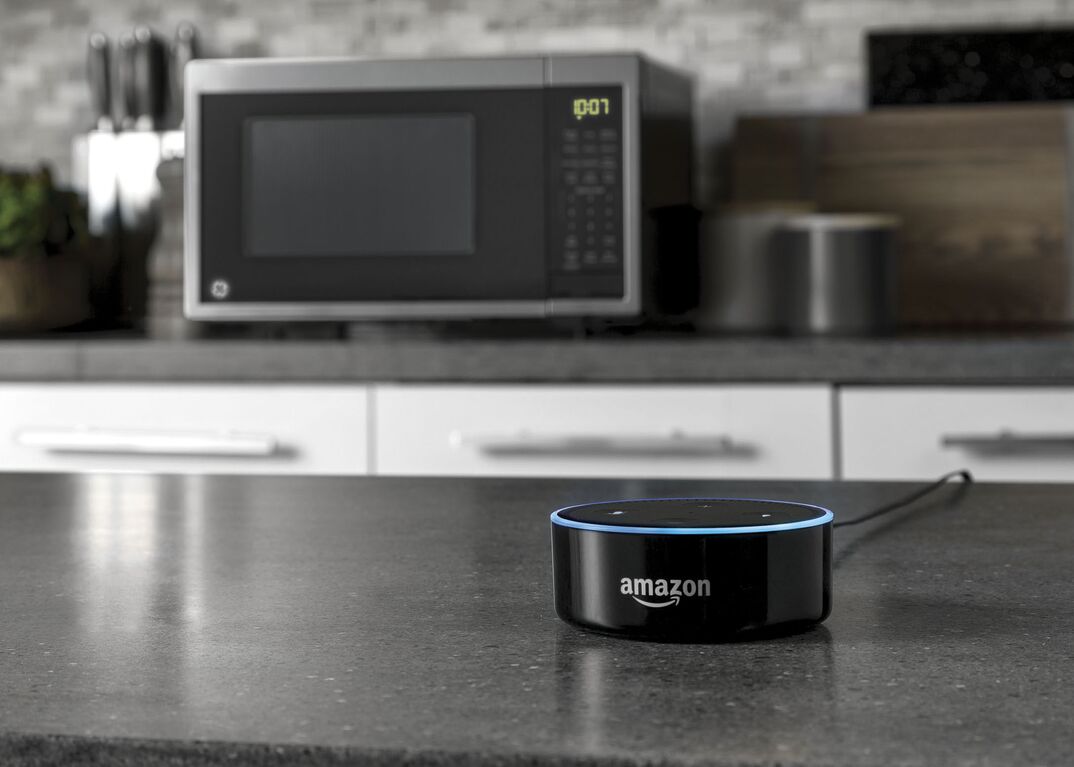 An Amazon smart home device sits on the kitchen island in the foreground and in the background on the kitchen counter sits a GE brand smart microwave