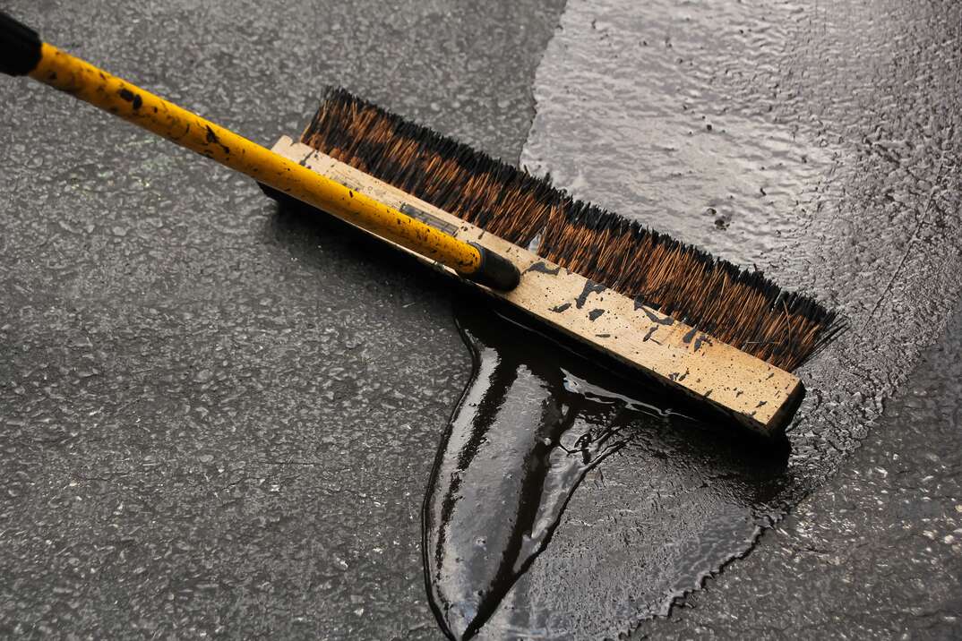 Broom being used to seal blacktop Asphalt Driveway