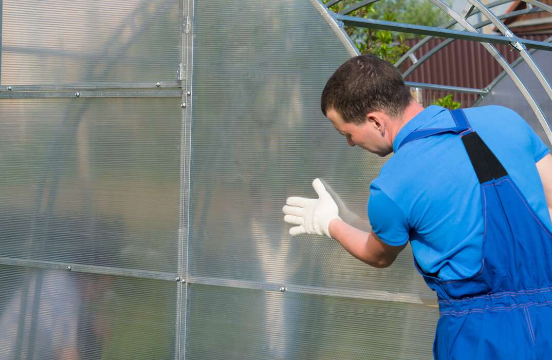 checking the correct installation of the greenhouse and polycarbonate on it workers in blue uniforms