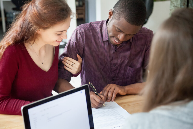 Multiracial couple signing documents at meeting, young african american black man putting signature on rental sale purchase agreement, mortgage bank loan for buying real estate, prenuptial agreement