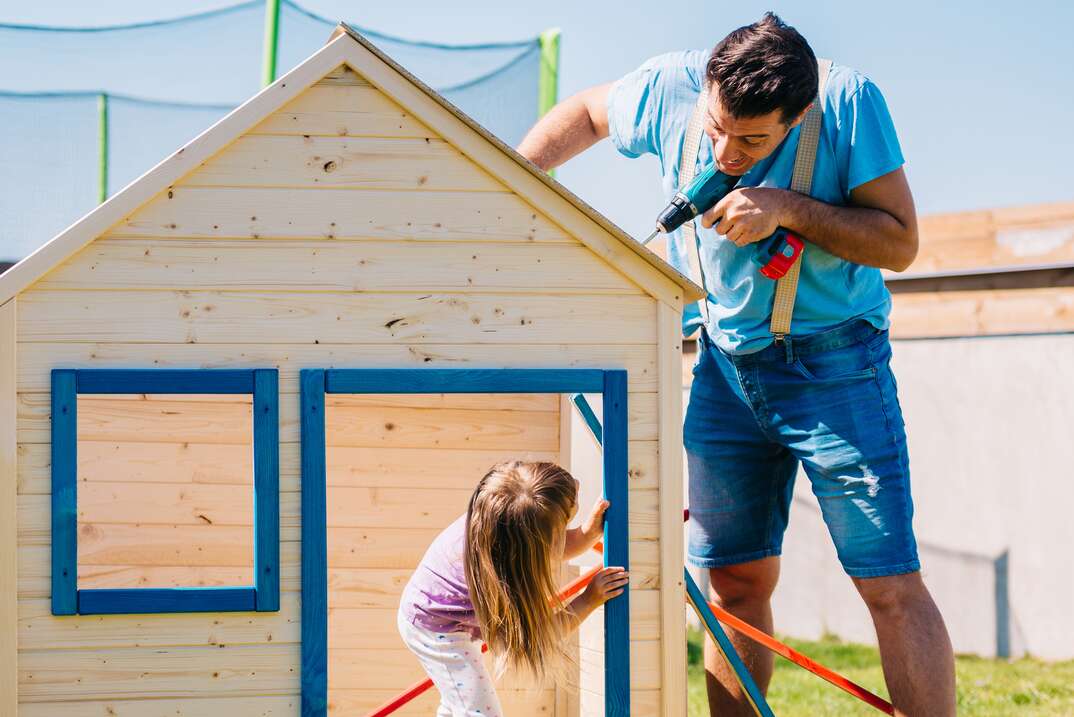 Father and daughter building a wooden house together