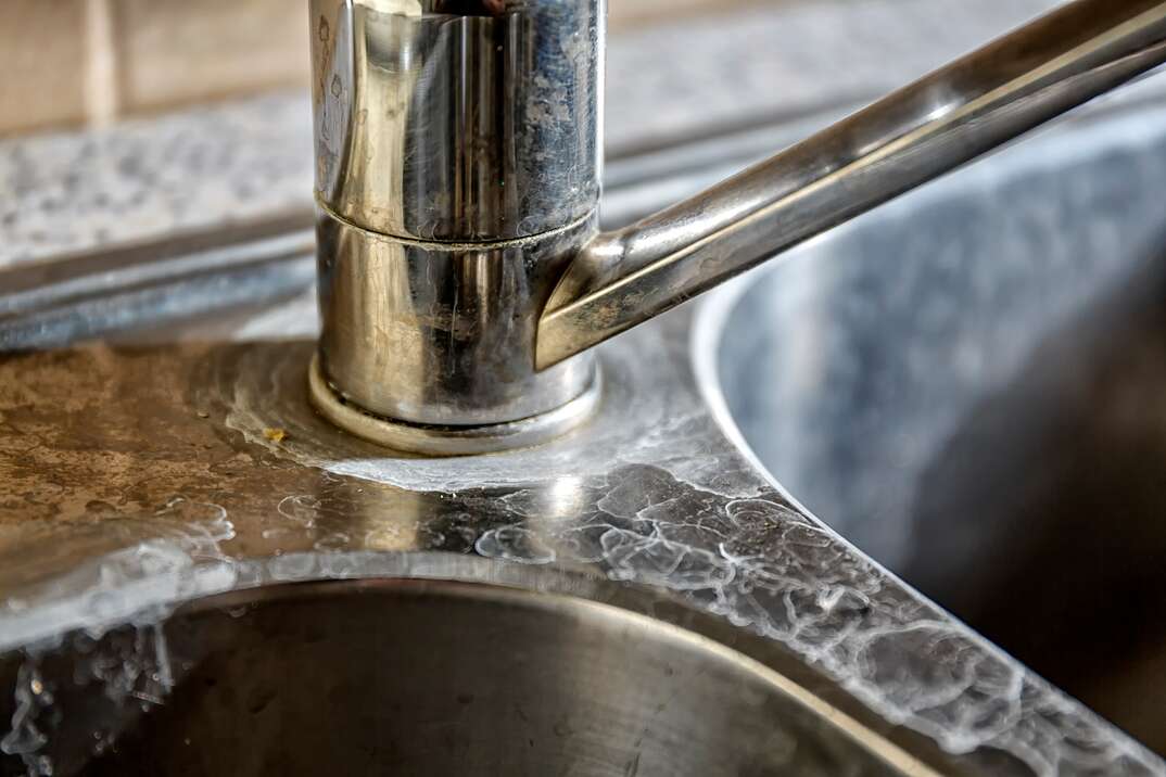 Close-up of a kitchen sink with lime scale