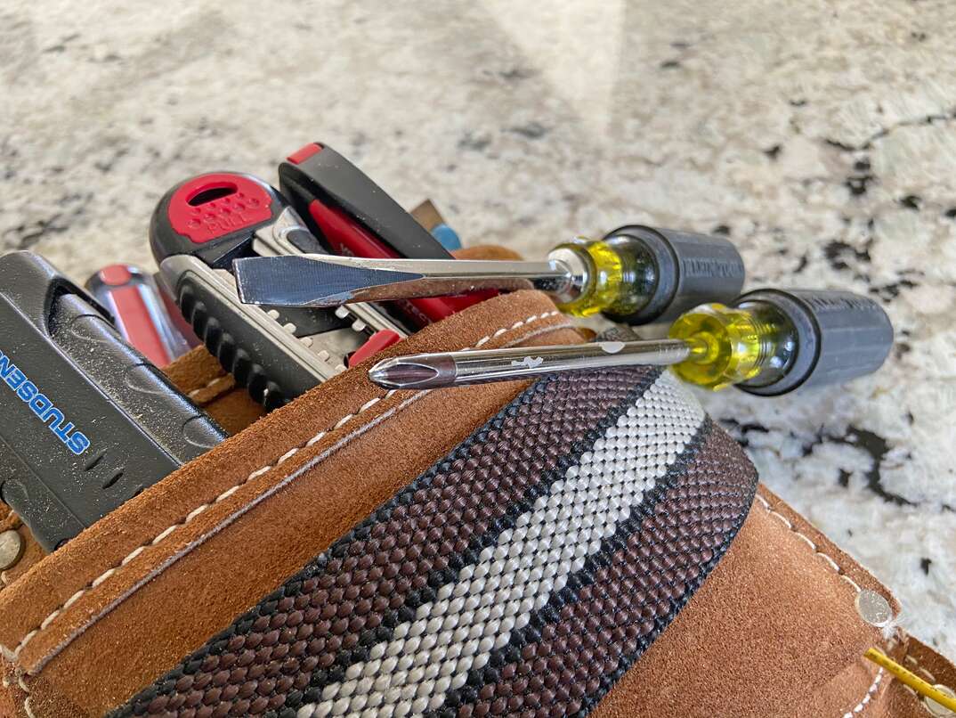 a set of Klein screwdrivers sits atop a leather tool pouch