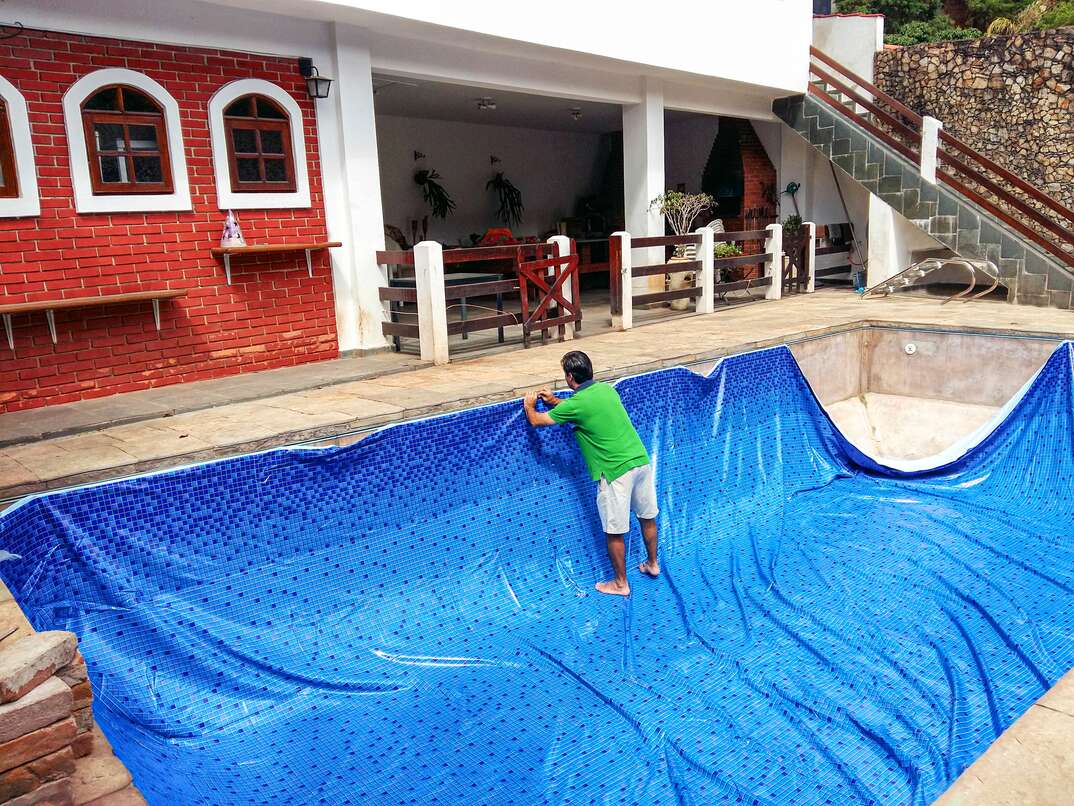 Man installing new pool liner on a concrete inground pool 