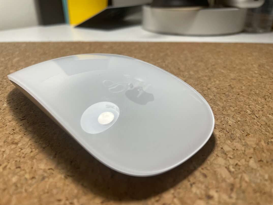 White Apple brand mouse on a desk