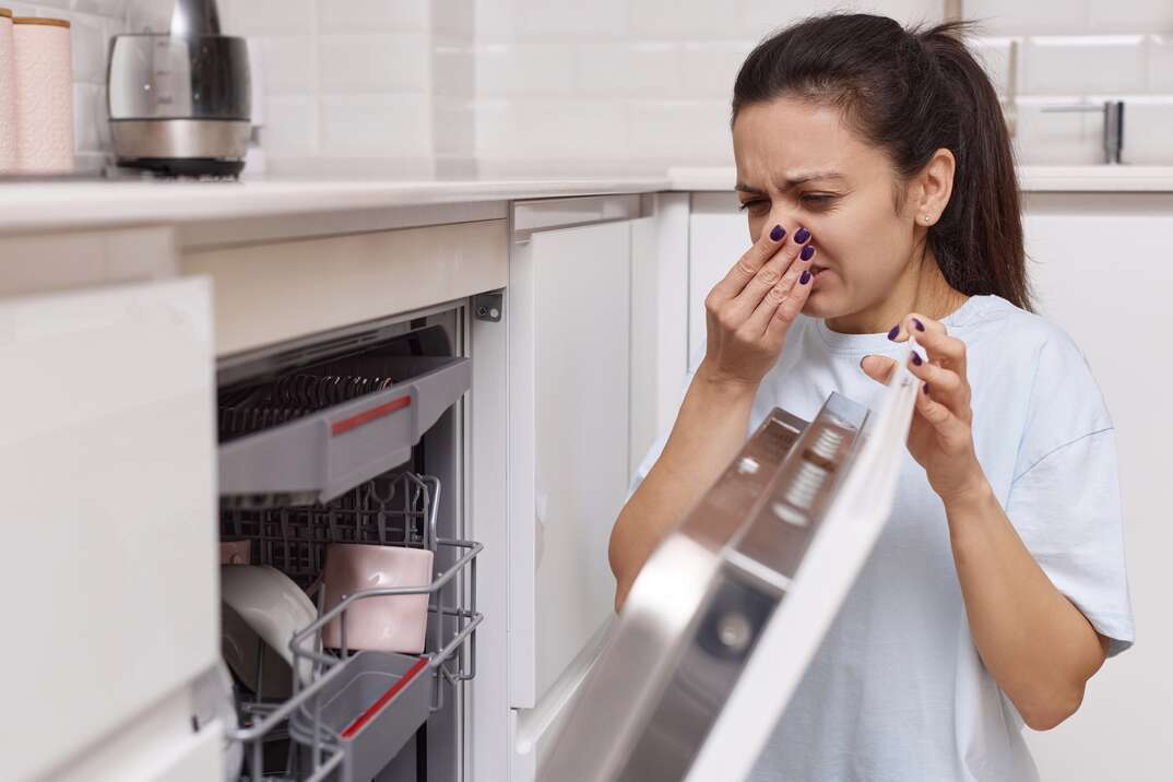 woman smells terrible smell coming from dishwasher machine