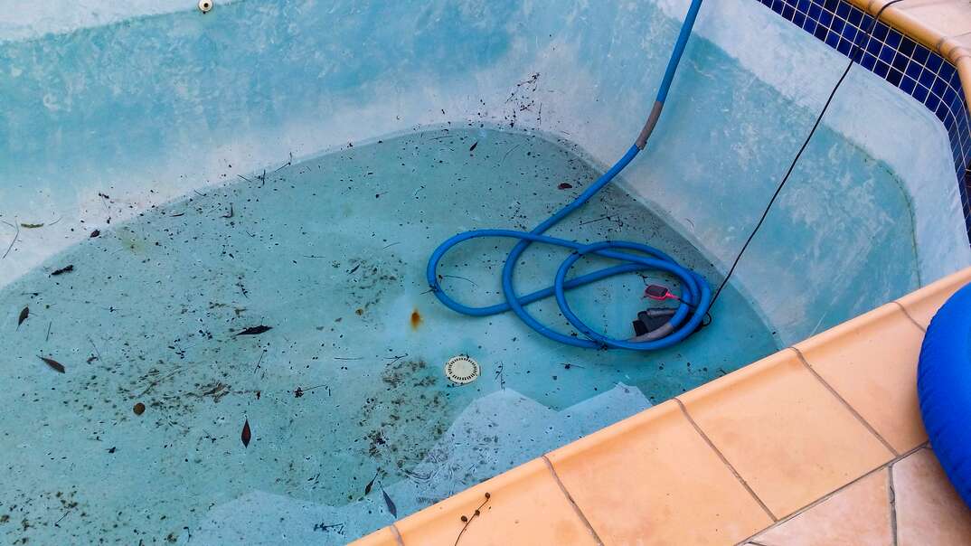 in-ground pool being drained with an electric submersible pump