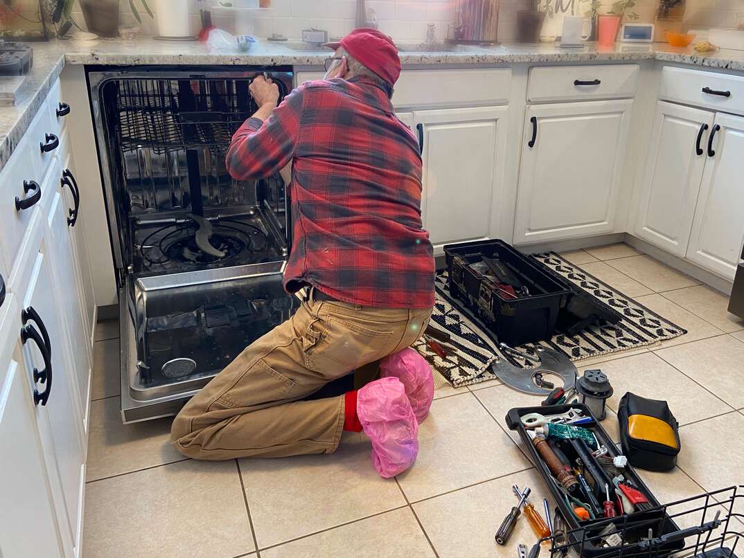 technician works to repair a residential diswasher