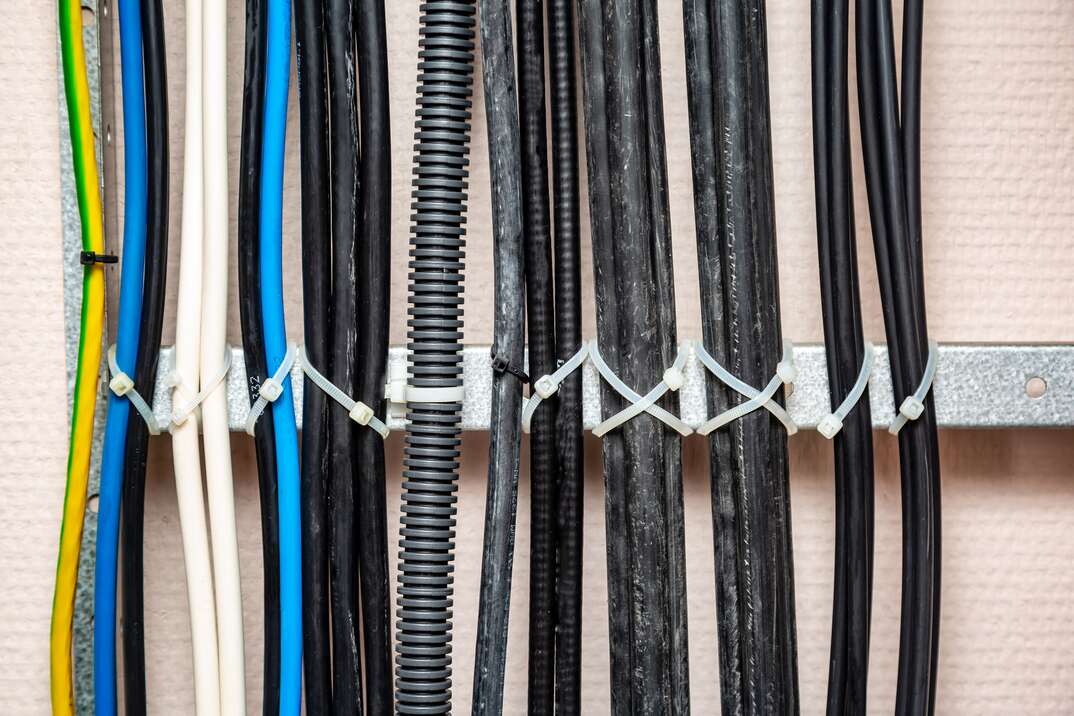Cables fastened with white ties on the cable ladder  Black, corrugated cable  Cable management  Close-up  Horizontal orientation, gray, ground wires, white, yellow