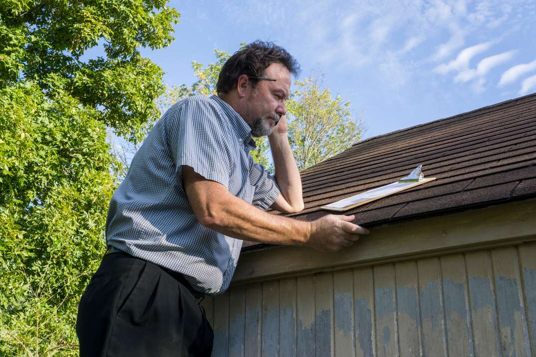 Insurance Adjuster Checking Roof For Hail Damage