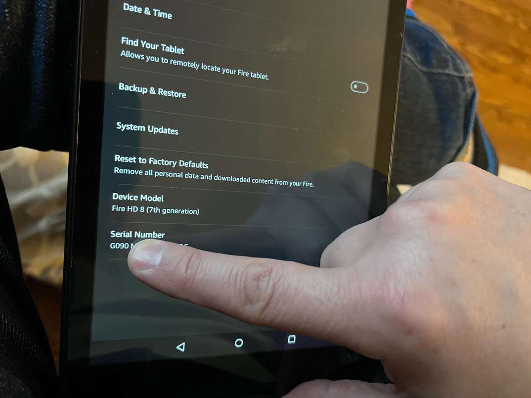 An Amazon Kindle Fire tablet device is held by a human hand