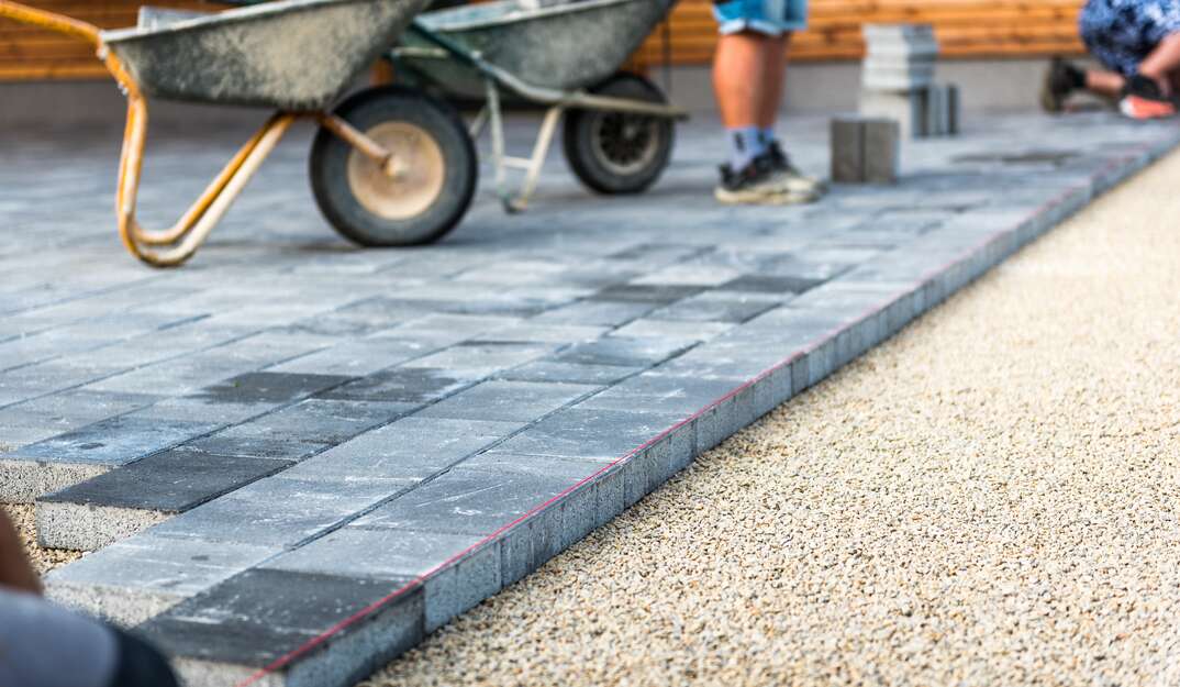 Laying gray concrete paving slabs in house courtyard driveway patio 