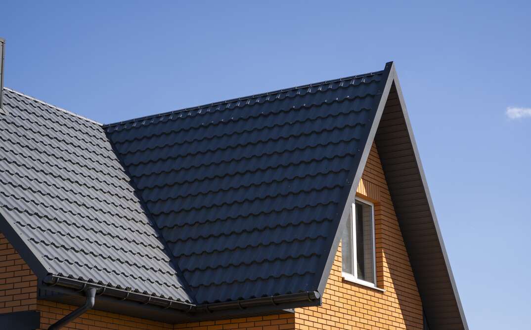 Grey corrugated metal profile roof installed on a modern house. The roof of corrugated sheet. Roofing of metal profile wavy shape. Modern roof made of metal. Metal roofing.