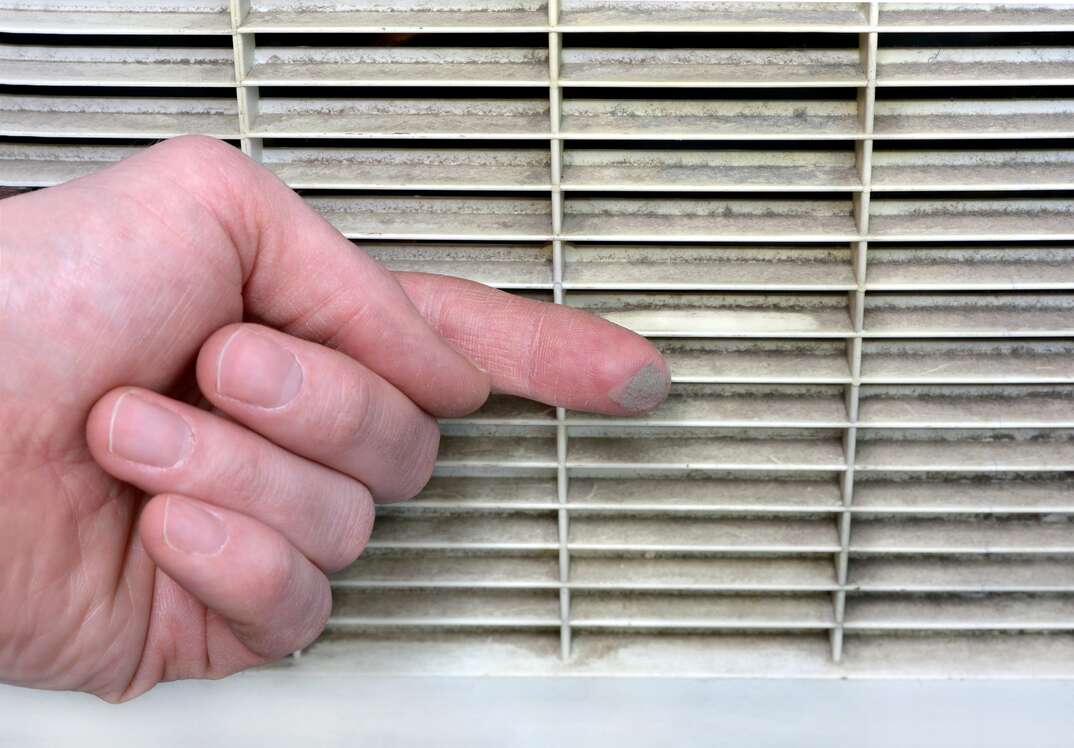 Person checks the grime of the vent grill by swiping a finger along it