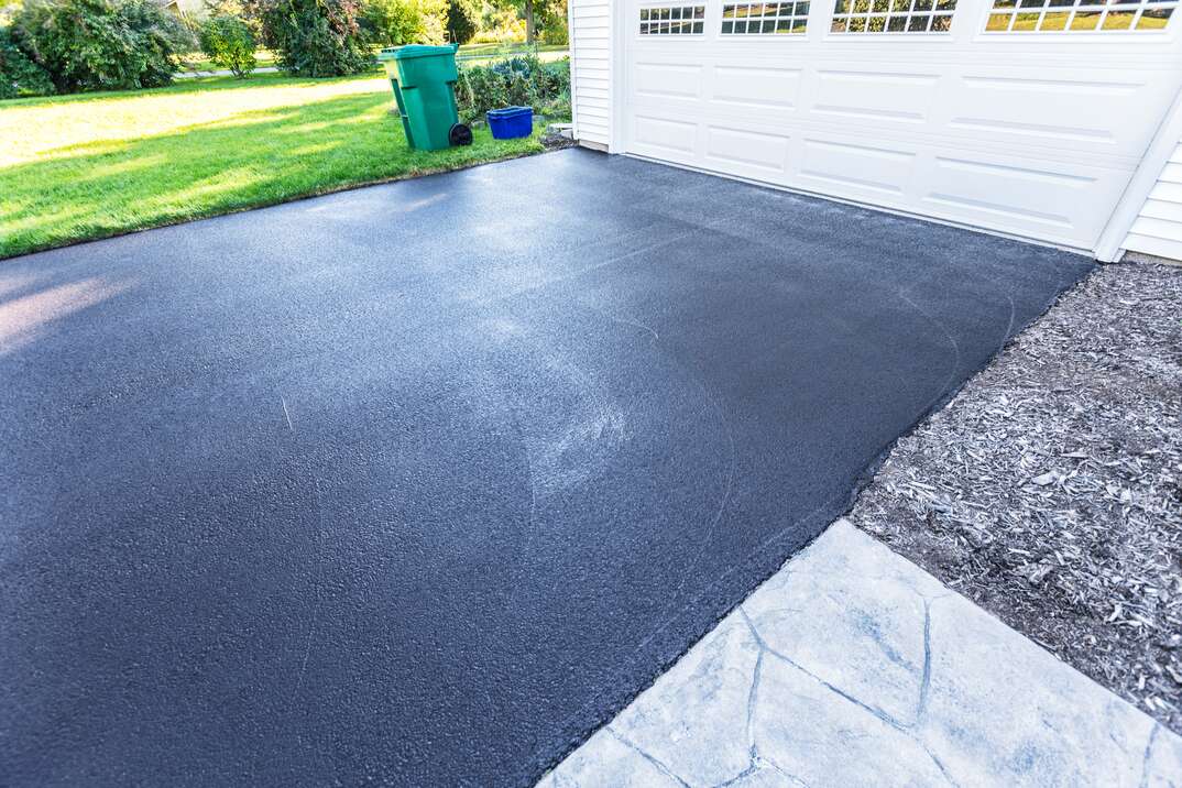 A fresh blacktop resealing job just finished on this asphalt driveway in a suburban residential