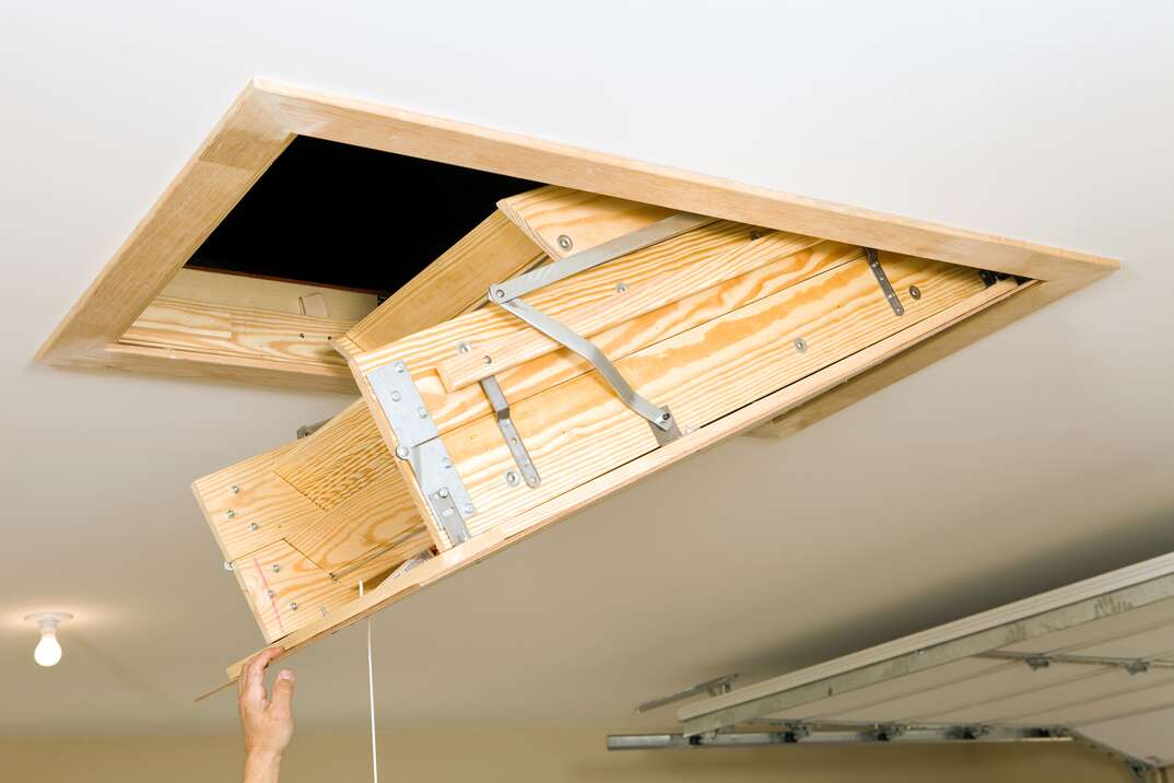 image of an attic pull down ladder being lowered from the ceiling 
