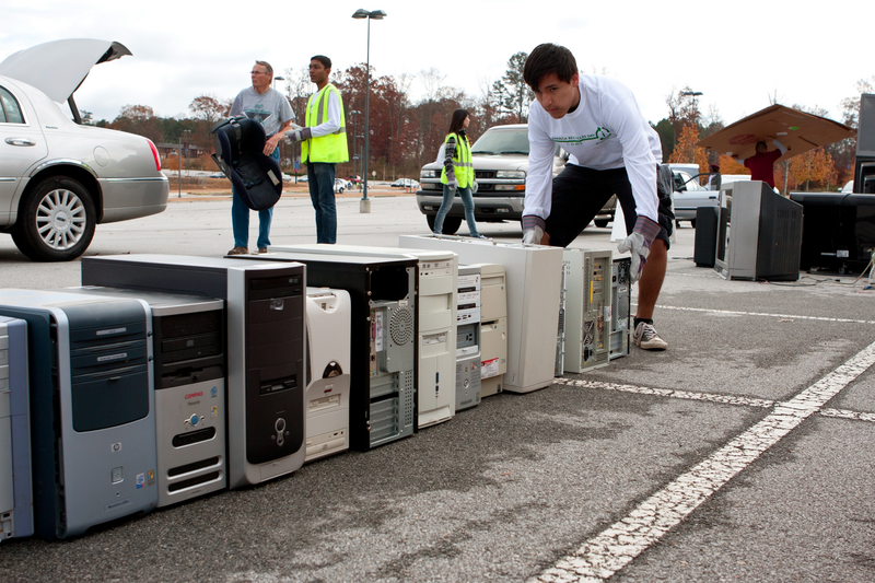 Lawrenceville, GA, USA - November 23, 2013:  A teen volunteer stacks a computer hard drive with other computer parts to be recycled at Gwinnett County's America Recycles Day event.