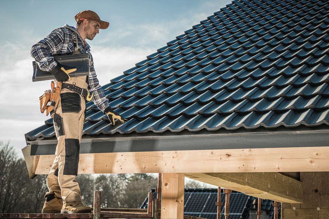 Male Caucasian Roofer Installing  Roofing Tiles On Newly Built Home.