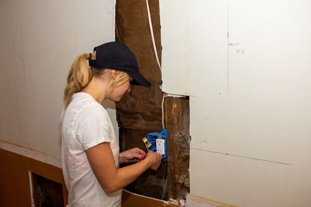 A young woman wiring a new electrical outlet as part of a DIY home improvement project.