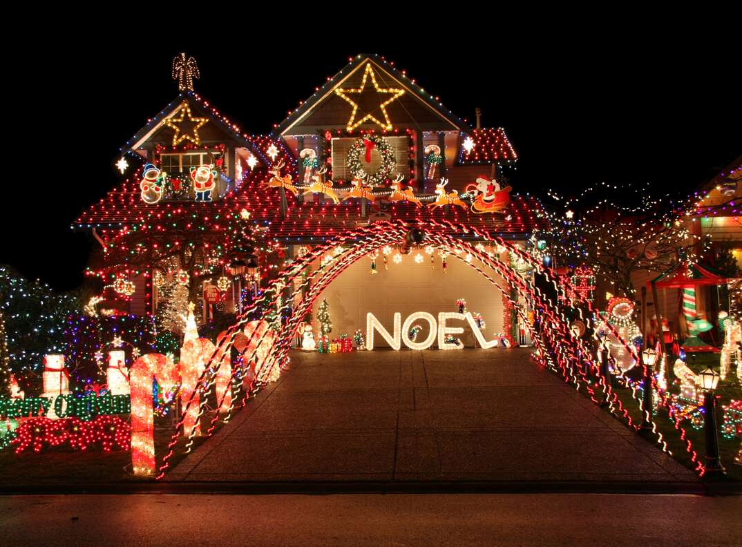 Front of a large house at night lit up by an over-the-top holiday light and decorations display.