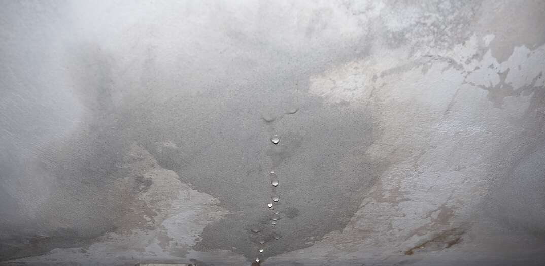 damage caused by dampness and moisture on a ceiling, with droplets of water infiltration