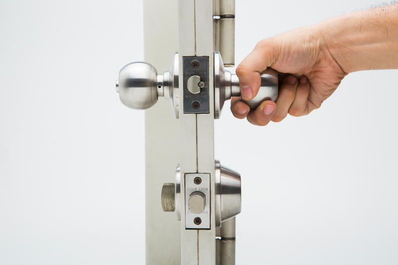 From a side view against a white background person's hand attempts to open a door using the silver metal doorknob, white background, silver metal doorknob, silver metal, doorknob, door, knob, hand, human, human hand