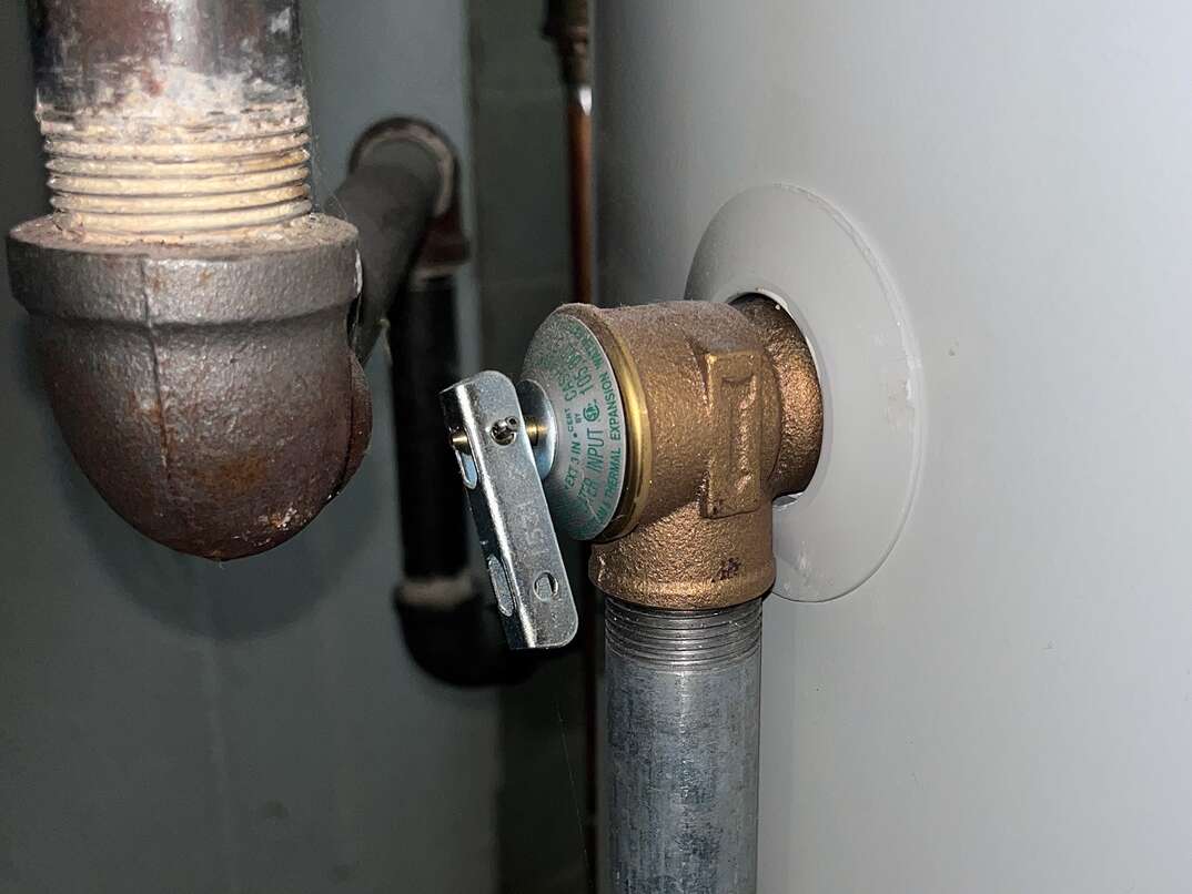 Close up of a water heater blow-off valve on a modern gas-powered high-efficiency water heater.