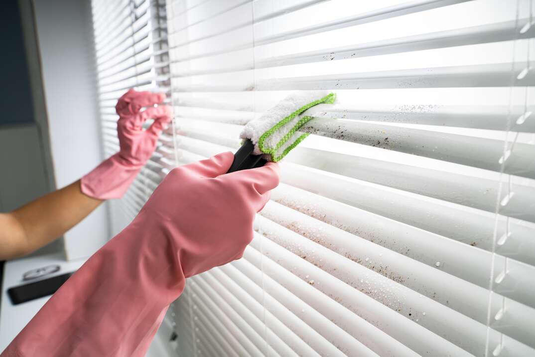 Person Cleaning Window Blinds