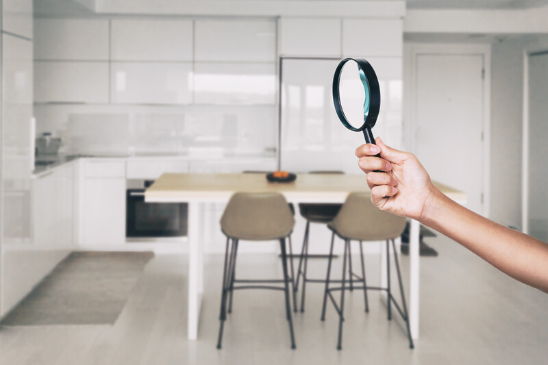 inspector with magnifying glass looking at the modern kitchen in the background during home inspection