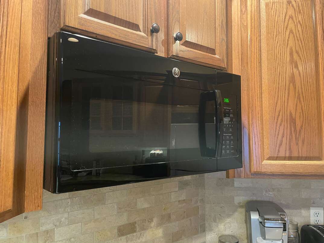black microwave mounted above the stove
