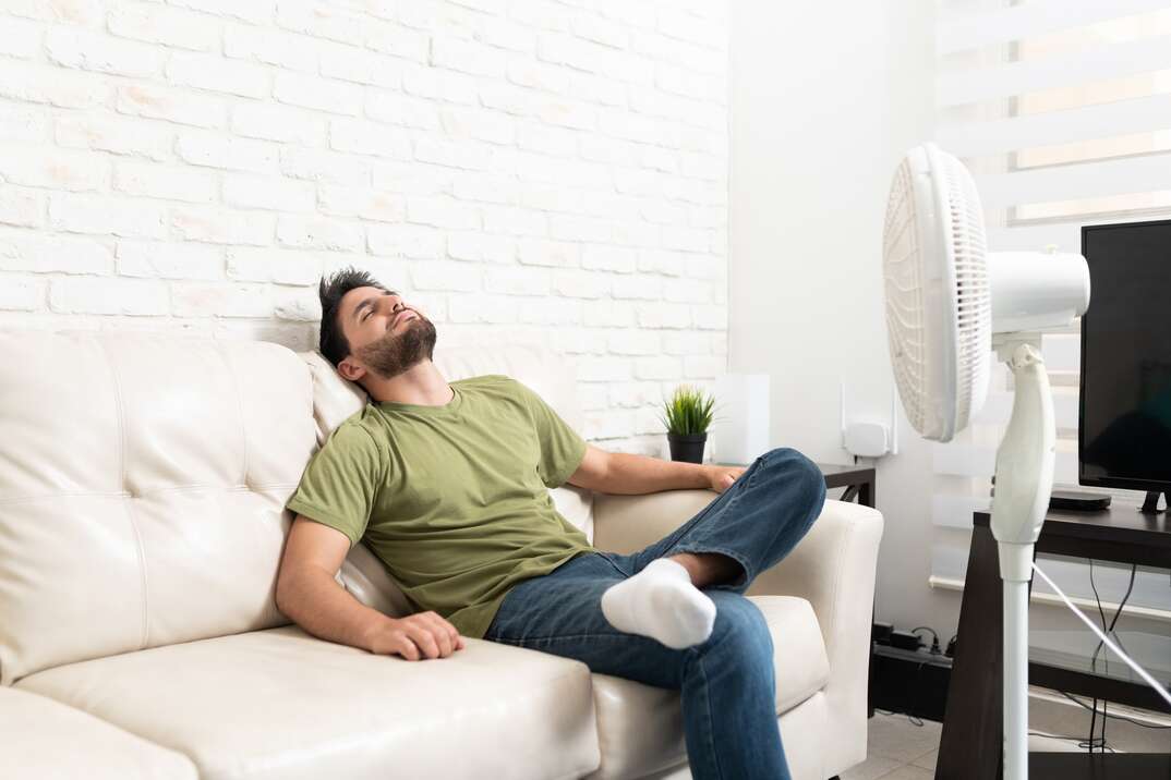Latin Man Relaxing In Front Of Fan At Home