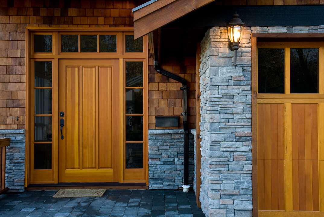 the entryway of a modern home with cedar siding and stone facade 