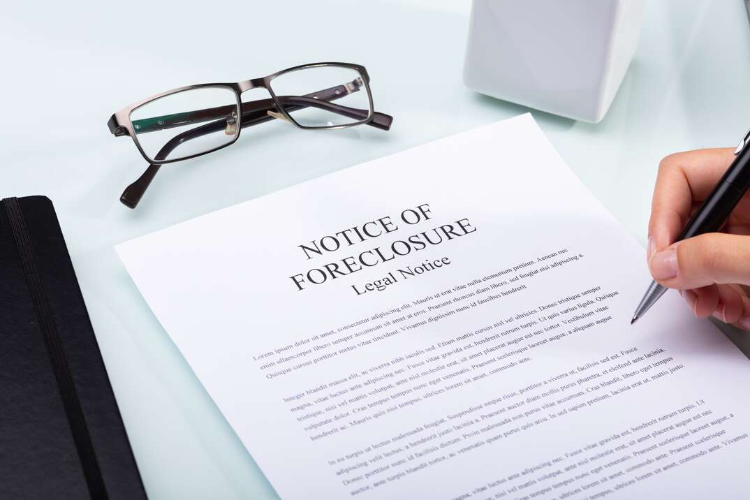 Close-up Of A Woman's Hand Holding Pen Over Notice Of Foreclosure Document