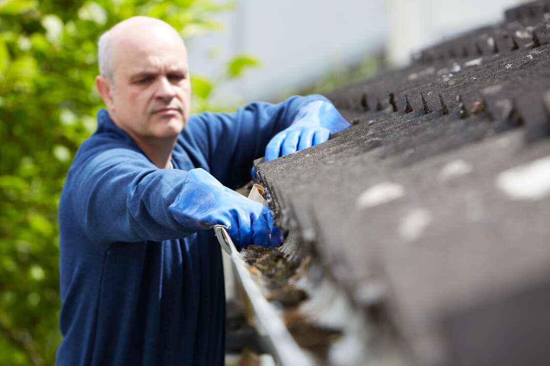 man cleaning out the gutters