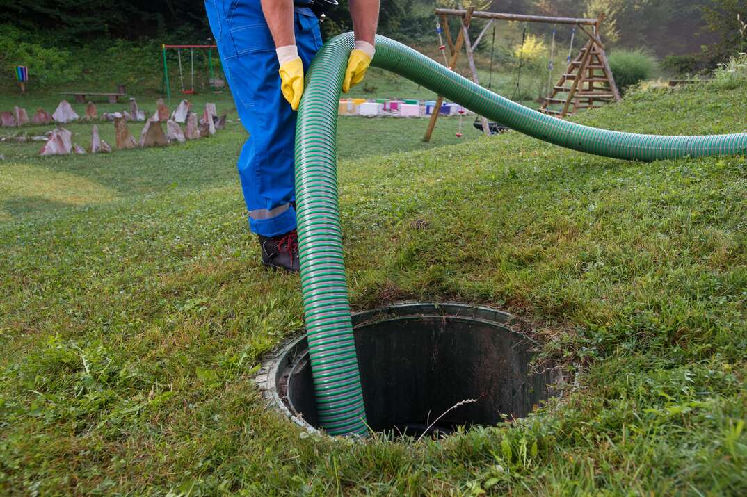 cleaning and unblocking the clogged drain by emptying the septic tank using a green tube