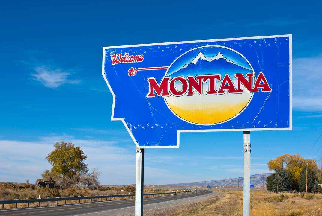 a Welcome to Montana sign sits alogside a highway