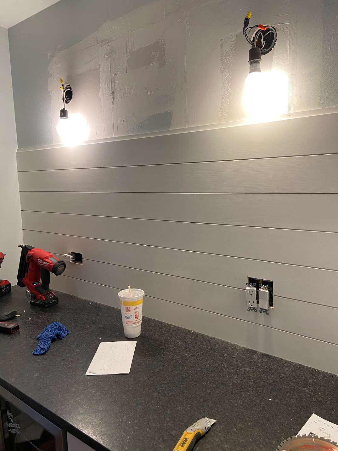 Shiplap board going up the wall of the dry bar using liquid nails and a power nailer