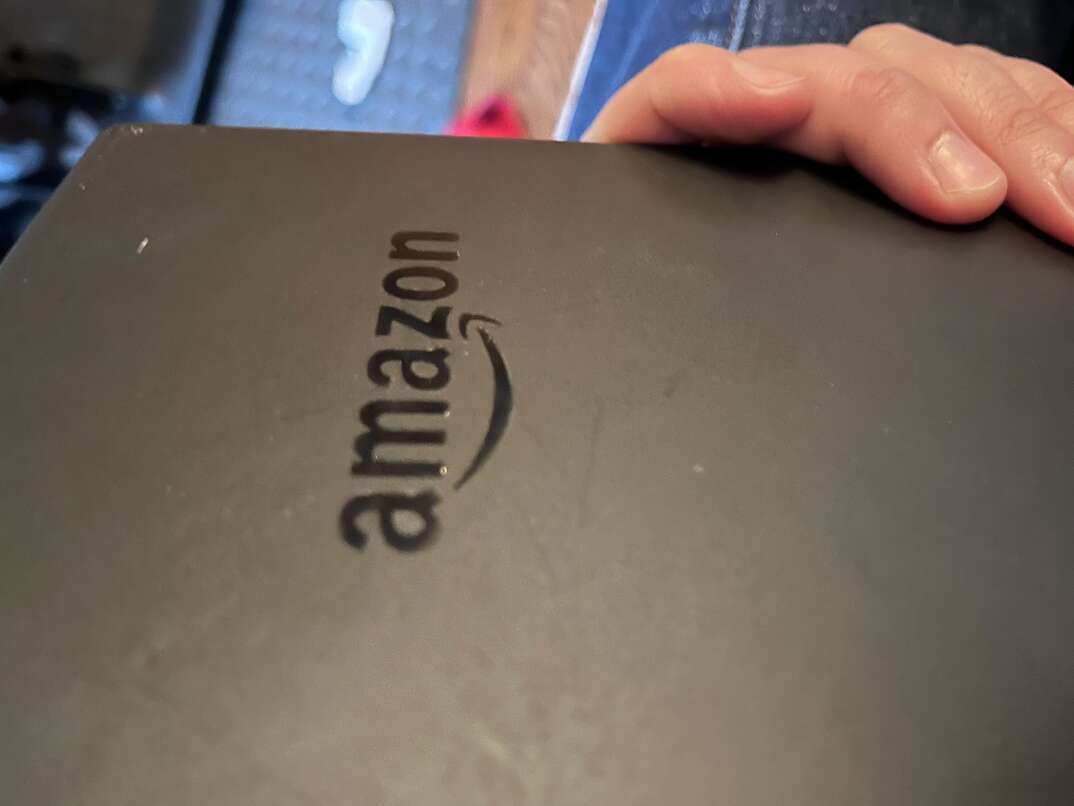 An Amazon Kindle Fire tablet device is held by a human hand