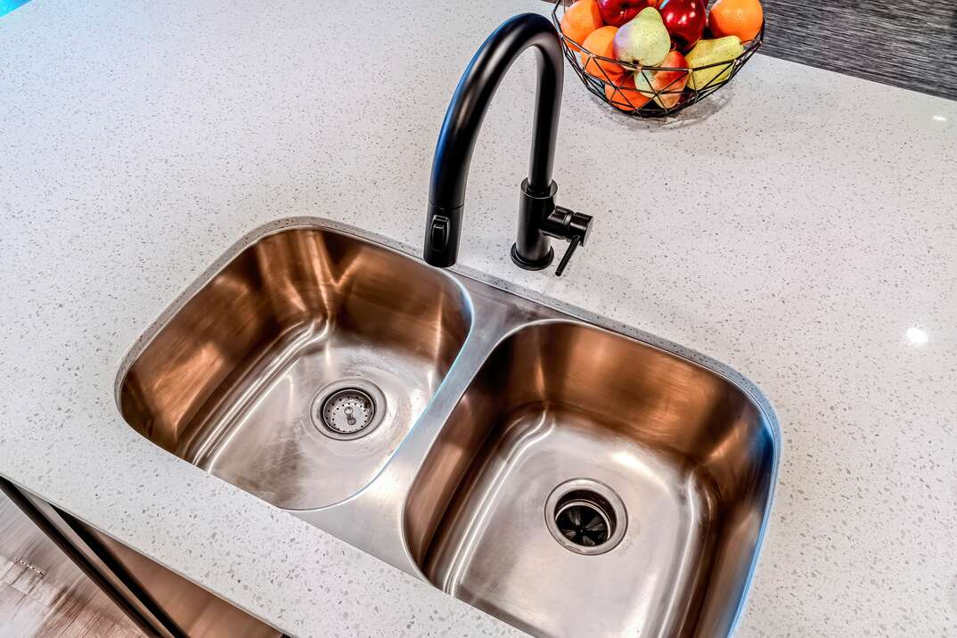 Top view of stainless steel double basin undermount sink and black curved faucet