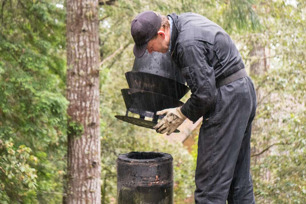 Man in overalls cleaning  on the roof of house cleaning dirty chimney