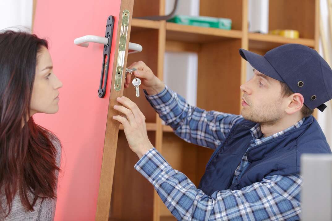 young smiling housewife meeting locksmith at home