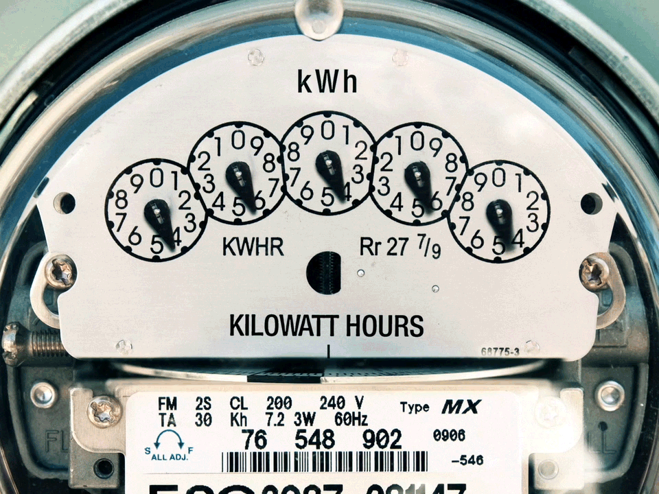 A close up of a residential electric usage meter running at full speed and showing high consumption.