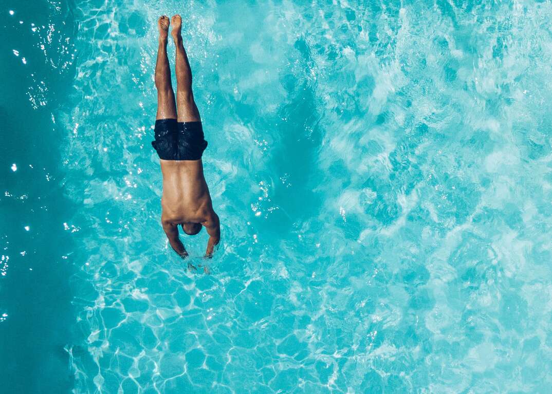 man diving into swimming pool