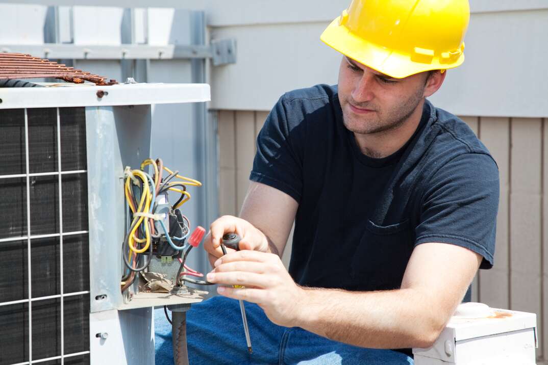 Young repairman fixing an industrial air conditioning compressor.