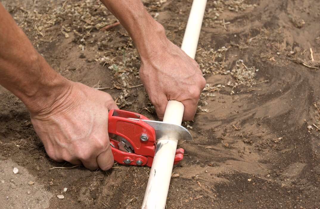 a worker cutting plastic pipes for a water supply pipe