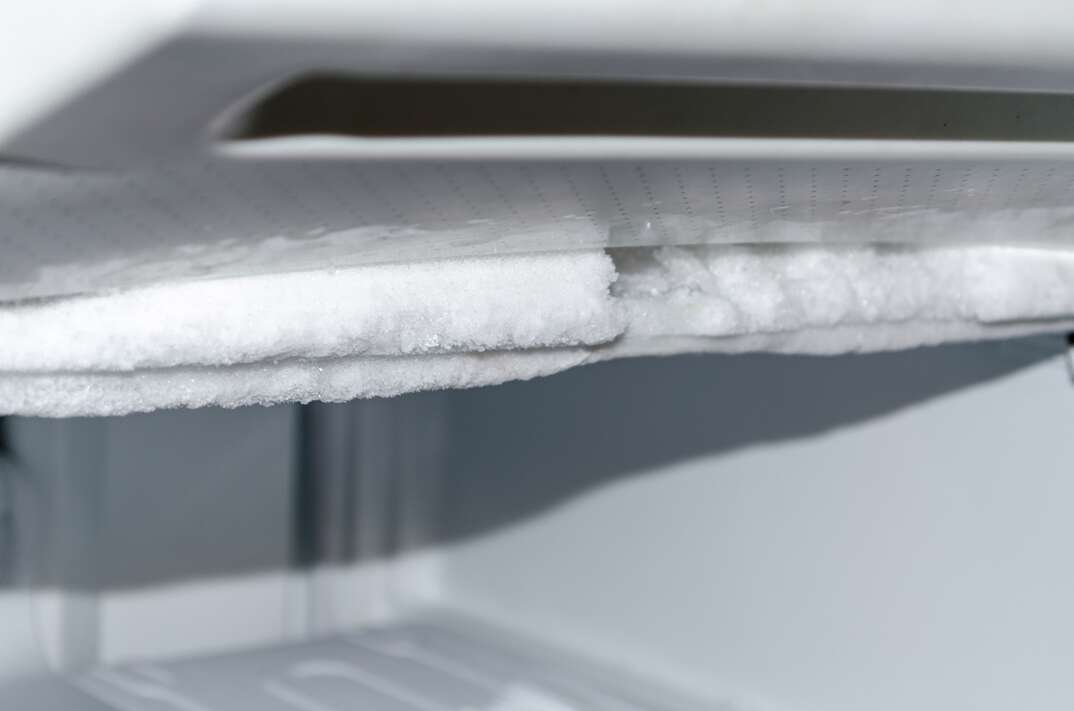 close up shot of a residential freezer covered in frost 