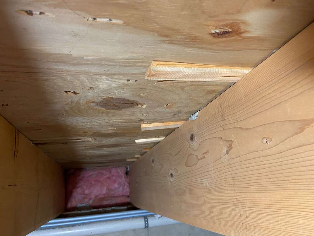 photo taken in a residential basement looking up at floor joists from the first level 