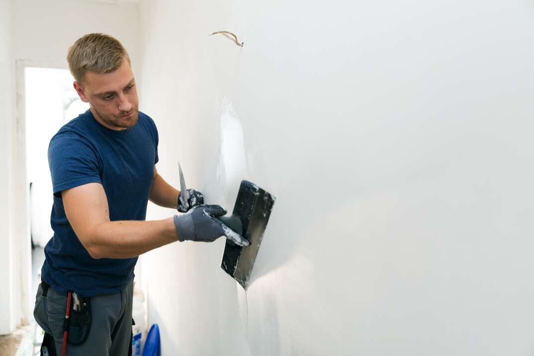 home improvement - construction worker with plastering tools renovating apartment walls